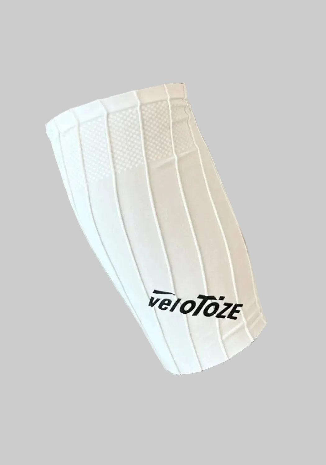 A white athletic knee sleeve with vertical compression panels and the black 'veloTOZE' logo near the bottom, shown on a plain white background.