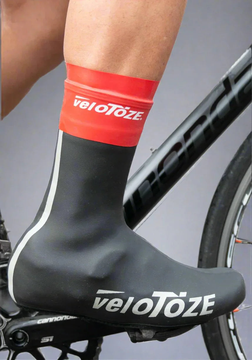 Cyclist wearing black and red waterproof cycling shoe cover on bike pedal