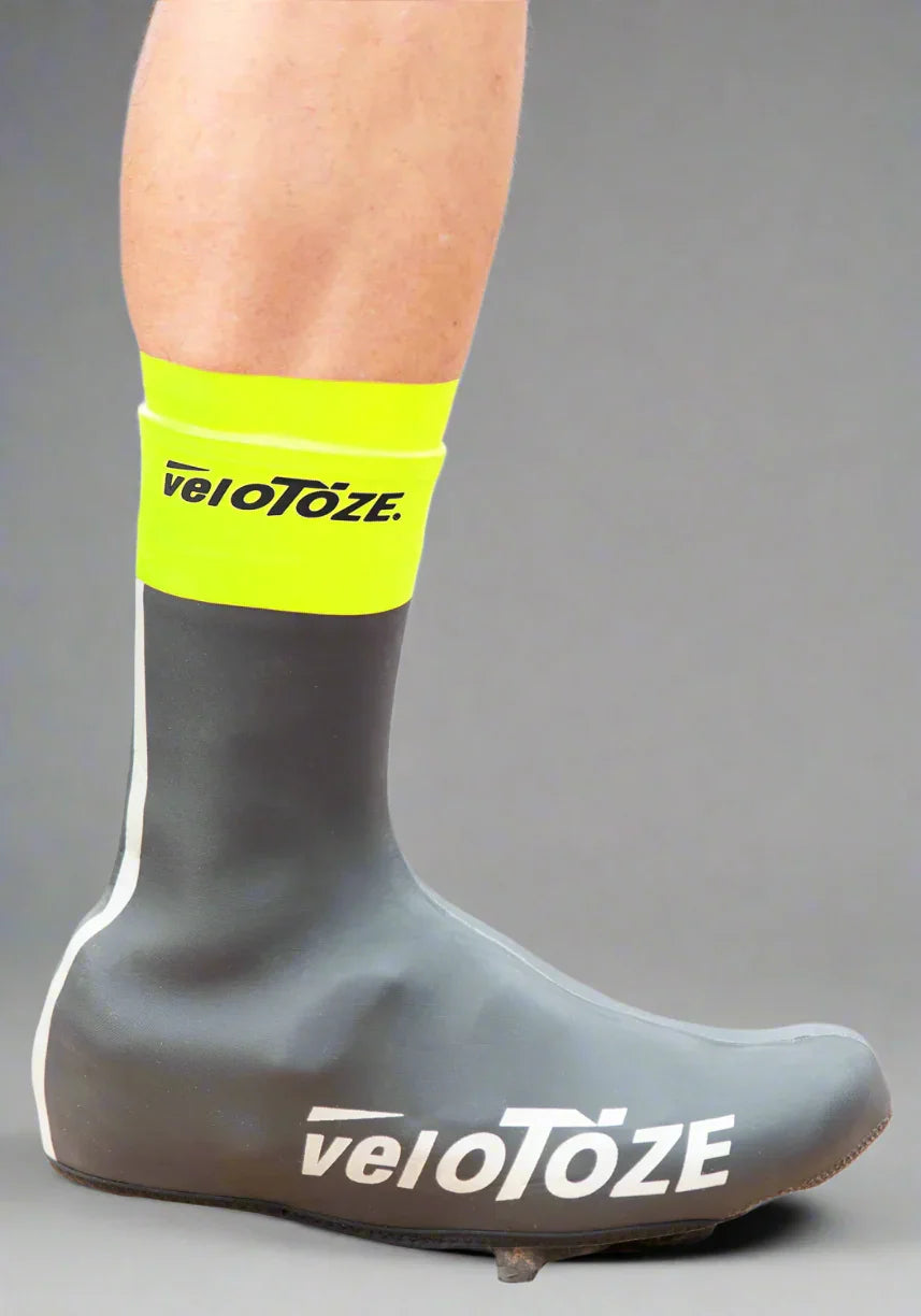 Yellow and black waterproof cycling shoe cover on leg, veloToze logo visible